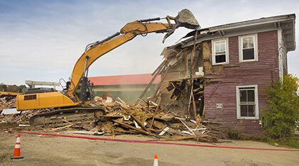 backhoe knocking down a house