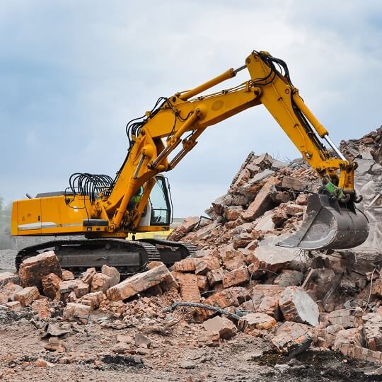 yellow backhoe with industrial debris